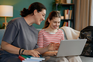 Wall Mural - Happy child and her mother are sitting on sofa