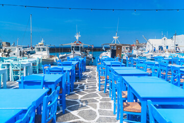 Canvas Print - Naoussa village harbour with mooring boats and blue cafe tables