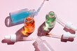 © ADDICTIVE STOCK - Colorful serum bottles with droppers on pink backdrop