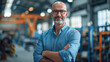 © Kowit - A man in a blue shirt and glasses stands in a factory