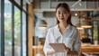 © win - Young Woman Holding a Tablet in a Modern Office Setting