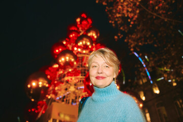 Outdoor portrait of happy 55 -60 year old woman visiting Christmas market in Lausanne, Switzerland