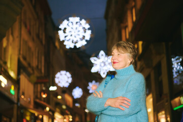 Outdoor portrait of happy 55 -60 year old woman visiting Christmas market in Lausanne, Switzerland