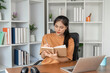 © wichayada - Young Woman Studying Online at Home with Laptop and Notebook in Modern Workspace