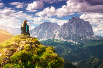 Wall Mural - sitting girl on the top with yellow flowers and green grass in beautiful alpine mountain valley at s