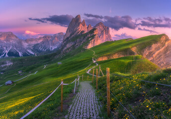 Wall Mural - Seceda mountain at beautiful sunset in summer in Dolomites, Italy. Colorful landscape with mountain peaks, rocks, alpine meadows, trail, green grass, purple sky at dusk. Hiking in Alps. Landscape