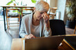 © Davor - Stressed professional senior woman using laptop in cafe
