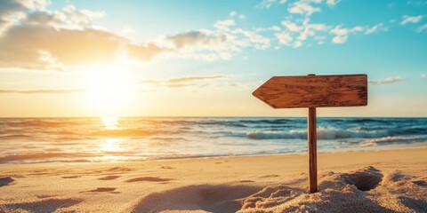 Wall Mural - A wooden sign is on the beach, pointing to the right. The sun is setting in the background, creating a warm and peaceful atmosphere