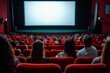 © Mickey - A group of people seated in a movie theater, facing a blank wide screen, anticipation and excitement for the upcoming film.  The red seats and darkened interior create an immersive cinematic experienc