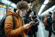 © Shubby Studio - A man in a brown jacket is looking at his phone while waiting for the train