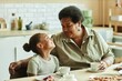 © Seventyfour - Medium shot of doting grandma looking with love and affection at smiling granddaughter while having tea at kitchen table