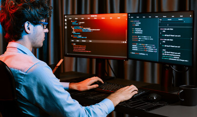 Working IT developer creating online software development information coding on pc screen at back side view, thinking program for latest version application on website at neon modern office. Gusher.