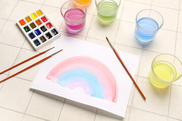 Wall Mural - Drawing of colorful rainbow with artist's paints, brushes and glasses on beige tile background