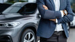 © khonkangrua - A confident businessman in a suit standing with arms crossed beside a luxury SUV, showcasing professionalism and success.