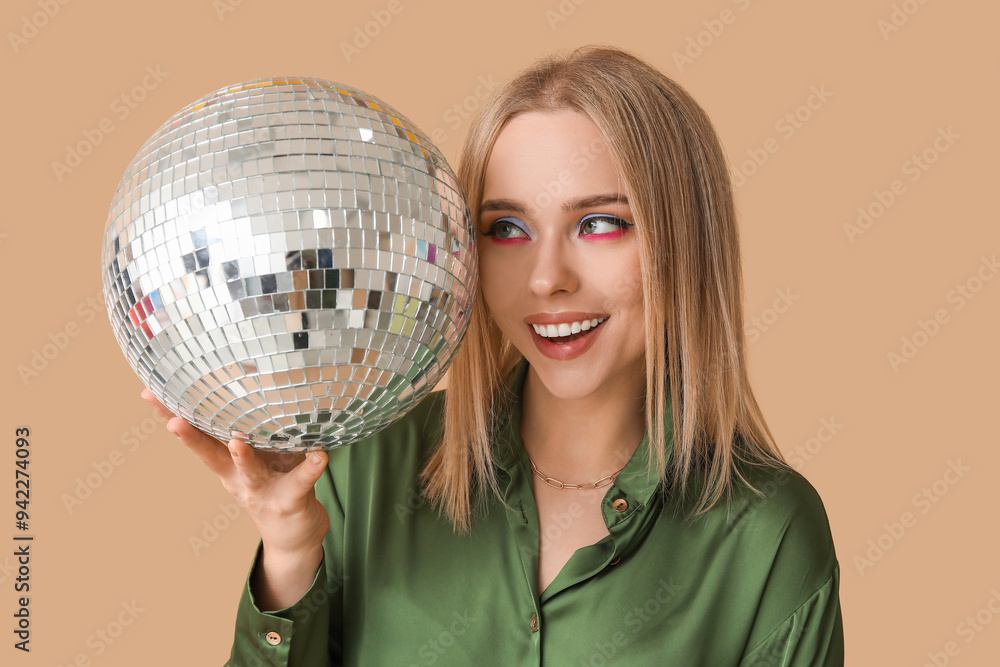 Beautiful young woman with disco ball on brown background