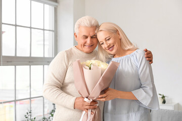 Wall Mural - Mature man giving his wife bouquet of roses at home