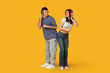 © Pixel-Shot - Beautiful young couple in headphones dancing on yellow background