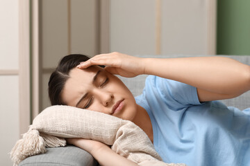 Canvas Print - Young woman suffering from headache and lying on sofa at home