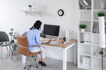 Canvas Print - Young woman writing on notebook at workplace with modern computer and laptop in light office