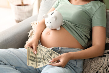 Canvas Print - Young pregnant woman with piggy bank and money sitting on sofa at home, closeup. Maternal Benefit concept