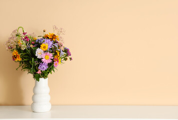 Wall Mural - Vase with wild flowers on table near beige wall in room. Closeup