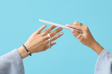 Wall Mural - Female hands with stylish manicure and nail file against color background, closeup