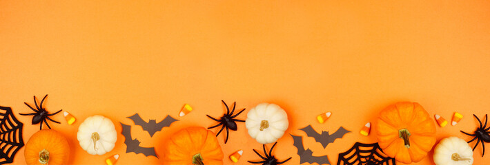 Aufkleber - Halloween bottom border of black, white and orange color candies, pumpkins and spooky decor. Overhead view on an orange banner background with copy space.