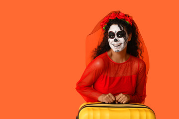 Wall Mural - Female African-American tourist dressed for Halloween with suitcase on orange background