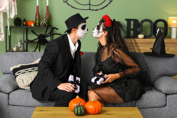 Sticker - Young couple dressed for Halloween with gift boxes kissing on sofa at home