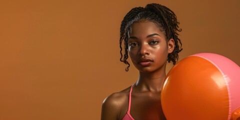 Wall Mural - A woman holds a colorful pink and orange ball, with a bright smile