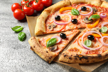 Cut delicious vegetarian pizza and tomatoes on grey table, closeup