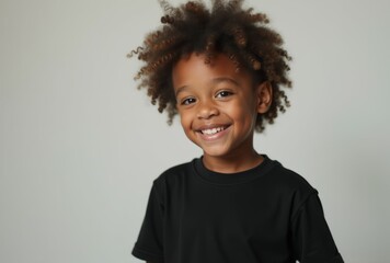 Wall Mural - A young boy with curly hair is smiling and wearing a black shirt