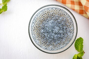 Wall Mural - Hairy basil seed in a glass cup  on white background, top view food table