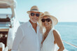 © lashkhidzetim - couple in white clothing and straw hats are smiling for the camera on a boat. Scene is happy and relaxed, as the couple appears to be enjoying their time together on the water