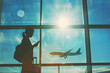 © Nhan - The silhouette of an traveler with luggage stands at the airport window, traveler waiting for the flight in airport, departure terminal, immigration concept