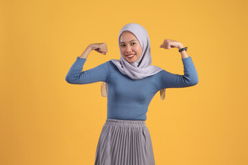 happy asian indonesian muslim woman cheerful expression with clenched fist on isolated yellow background