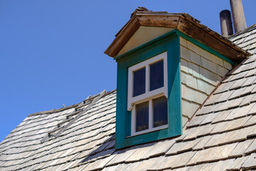 Green wooden window on the roof of an old wooden house