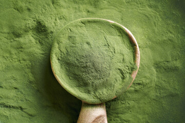 Wall Mural - Green chlorella algae powder on a wooden spoon, top view