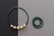 © Roman - Straw and bead necklace and green beaded bracelet. Green beaded. Gray background