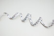 © ADDICTIVE STOCK - Top view of a coiled measurement tape on a white background
