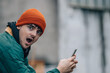 © carballo - portrait of young man with hat and warm clothes looking at mobile phone surprised