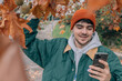© carballo - portrait of young man in hat using mobile phone in autumn with autumn leaves