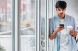 © carballo - young man with mobile phone and cup at home window