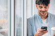 © carballo - young man with mobile phone and cup at home window