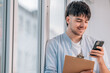 © carballo - young man with mobile phone and documents next to the window