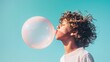 © VK Studio - A curly-haired boy blows a big bubble gum bubble under a bright blue sky, capturing a carefree summer moment.
