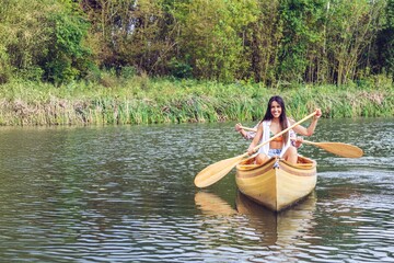 Two women paddling a canoe in a serene nature setting.