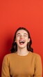 © AucArtStudio - happy young woman laughing out loud against red background studio portrait.