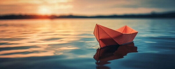 Wall Mural - Lone paper boat drifting on calm water as the sun sets in the background