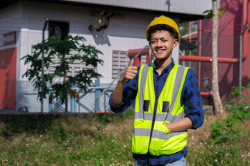 A young asian contractor raises his thumbs as a sign of satisfaction and success for the progress of his work.